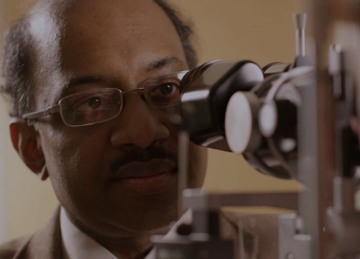 Dr Jayakrishna Ambati looking into a microscope - macular degeneration research [Credit: UVA Health].