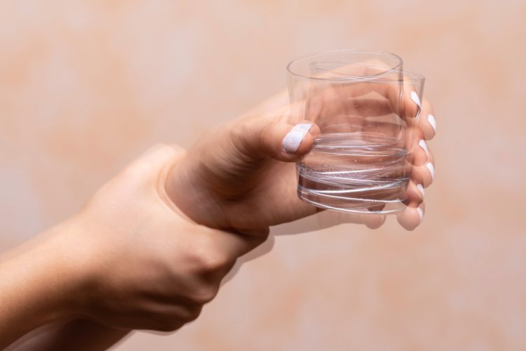 Shaky image of hand holding glass of water, indicating Parkinson's disease