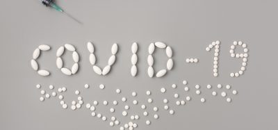White pills spelling out COVID-19 on grey background
